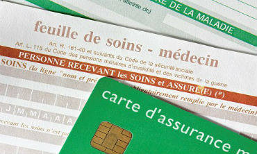 Feuilles de soins avec carte assurance maladie en premier plan