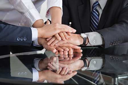 Superposition de mains de businessmen et businesswomen symbolisant la cohésion et le partenariat